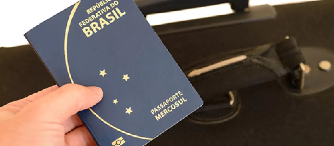 Mão segurando um passaporte brasileiro